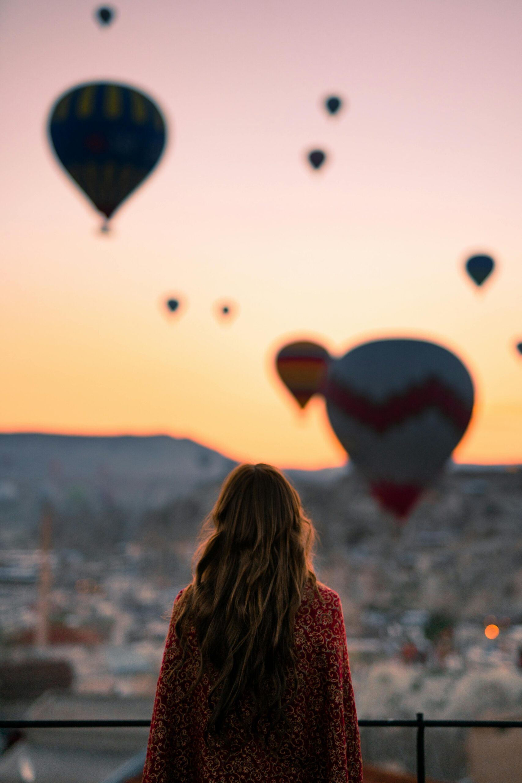 woman ready to rise watching the sunset and hot air balloons